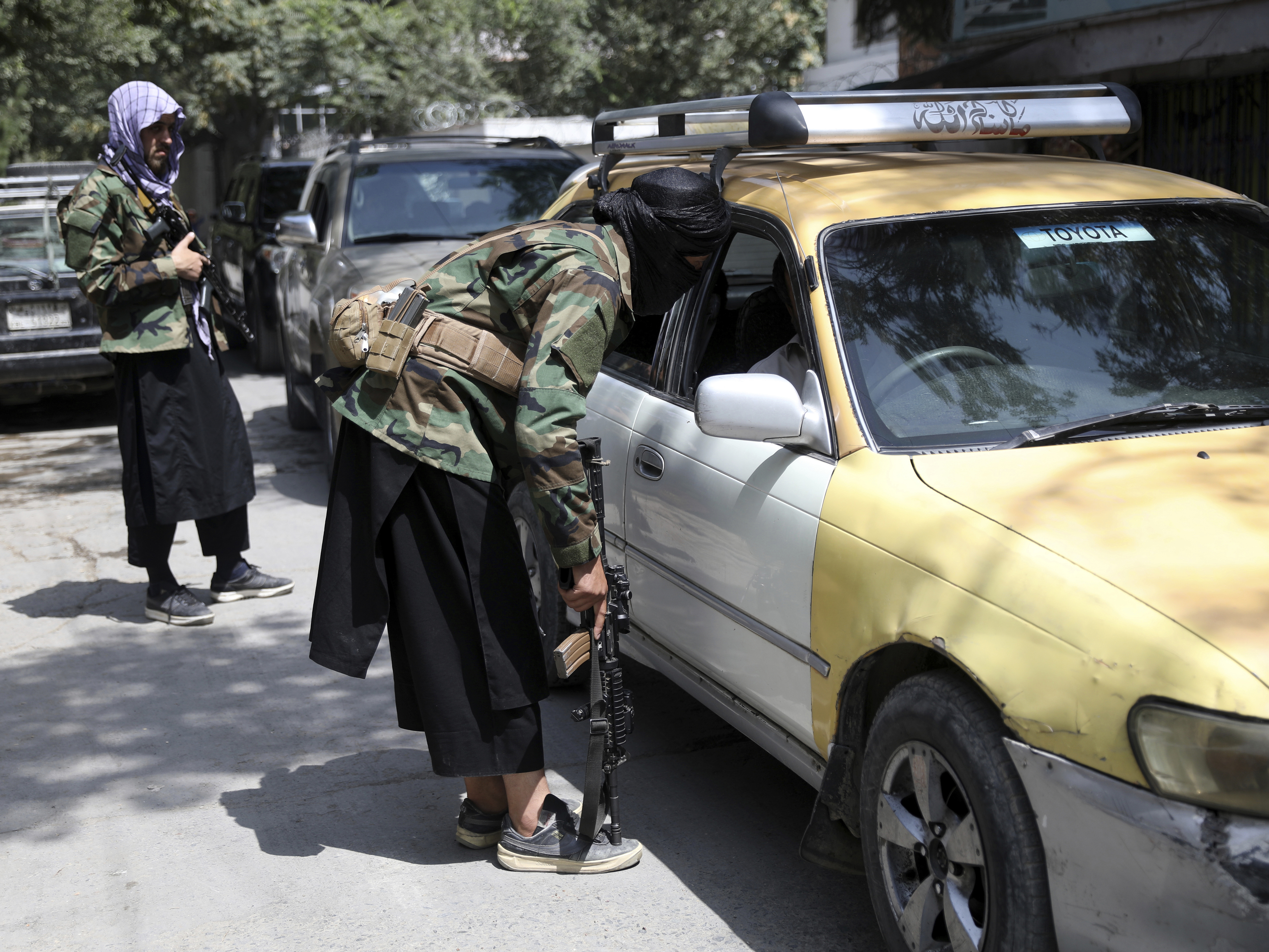 caption: Taliban fighters search a vehicle at a checkpoint on the road in the Wazir Akbar Khan neighborhood in the city of Kabul, Afghanistan in August.