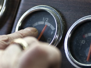 caption: A truck driver points to his fuel gauge in 2008. The Biden administration is now proposing to increase the fuel efficiency of cars and trucks.