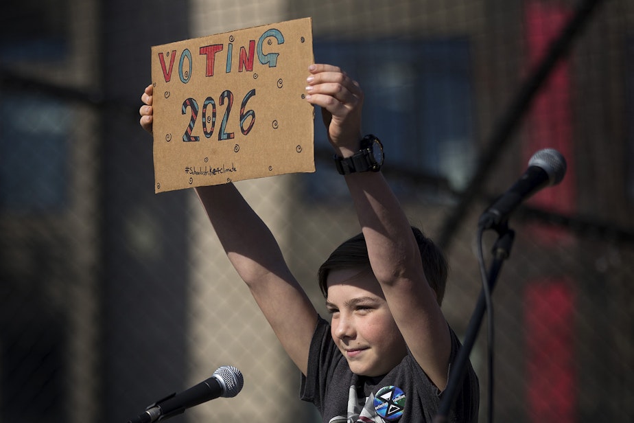 caption: FILE: Taro Moore, a 12-year-old student at Kenmore Middle School, holds up a sign after speaking to a crowd of hundreds during a student-led strike against climate change on Friday, March 15, 2019, at Cal Anderson Park in Seattle. 