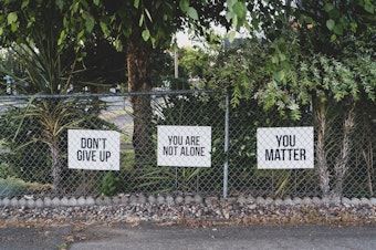 caption: Signs on a fence that contain positive messages to inspire hope.