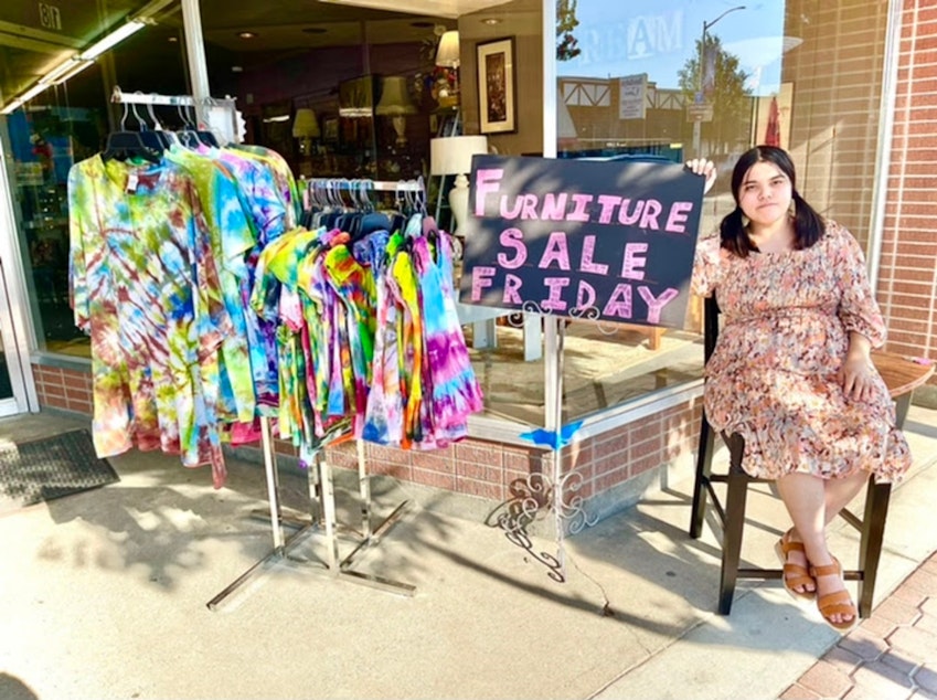 caption: Kit Nelson-Mora sells furniture at their mom’s thrift store, The Storehouse Merchantile, in Omak, Wash., in the summer of 2021.