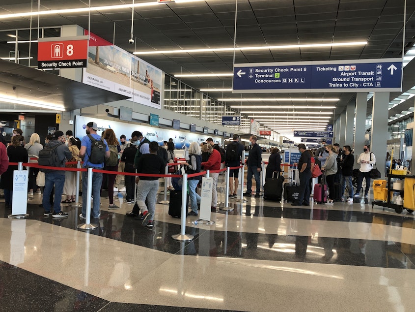 caption: A line loops through security at Chicago's O'Hare International Airport as travelers return to the skies after mostly staying home during the coronavirus pandemic.