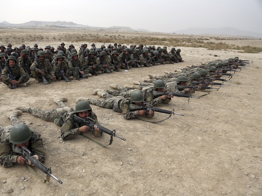 caption: A group of Afghan National Army soldiers watch others participate in a live fire exercise at the Afghan Military Academy last October in Kabul, Afghanistan.