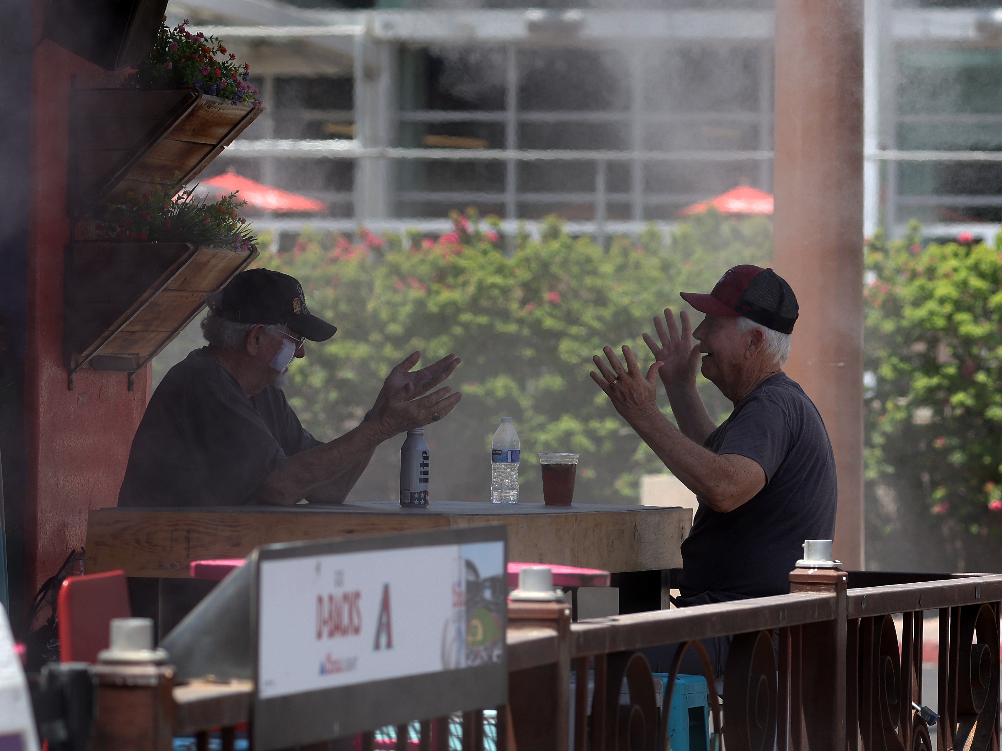 caption: People chat while having drinks under a mister at a restaurant in Phoenix on Wednesday. According to the National Weather Service, Phoenix will experience record temperatures soaring over 100 degrees due to a heat dome stemming from high pressure in the atmosphere. 