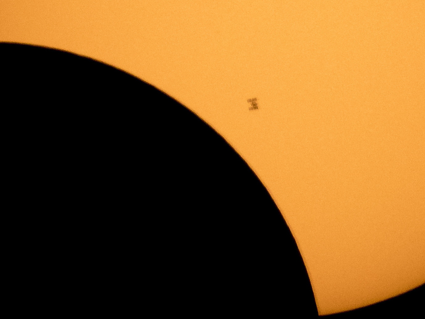 caption: In this image made available by NASA, the International Space Station is silhouetted against the sun during a solar eclipse Monday, Aug. 21, 2017, as seen from Ross Lake, Northern Cascades National Park in Washington state.