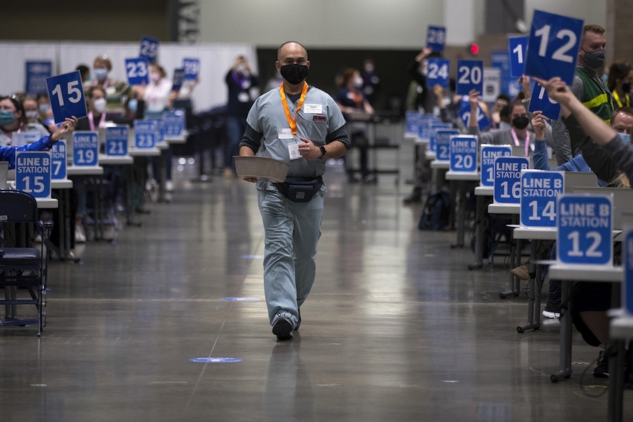 caption: Edgardo Santiago walks through one aisle of the new civilian-led mass Covid-19 vaccination site at Lumen Field Event Center on Saturday, March 13, 2021, in Seattle.