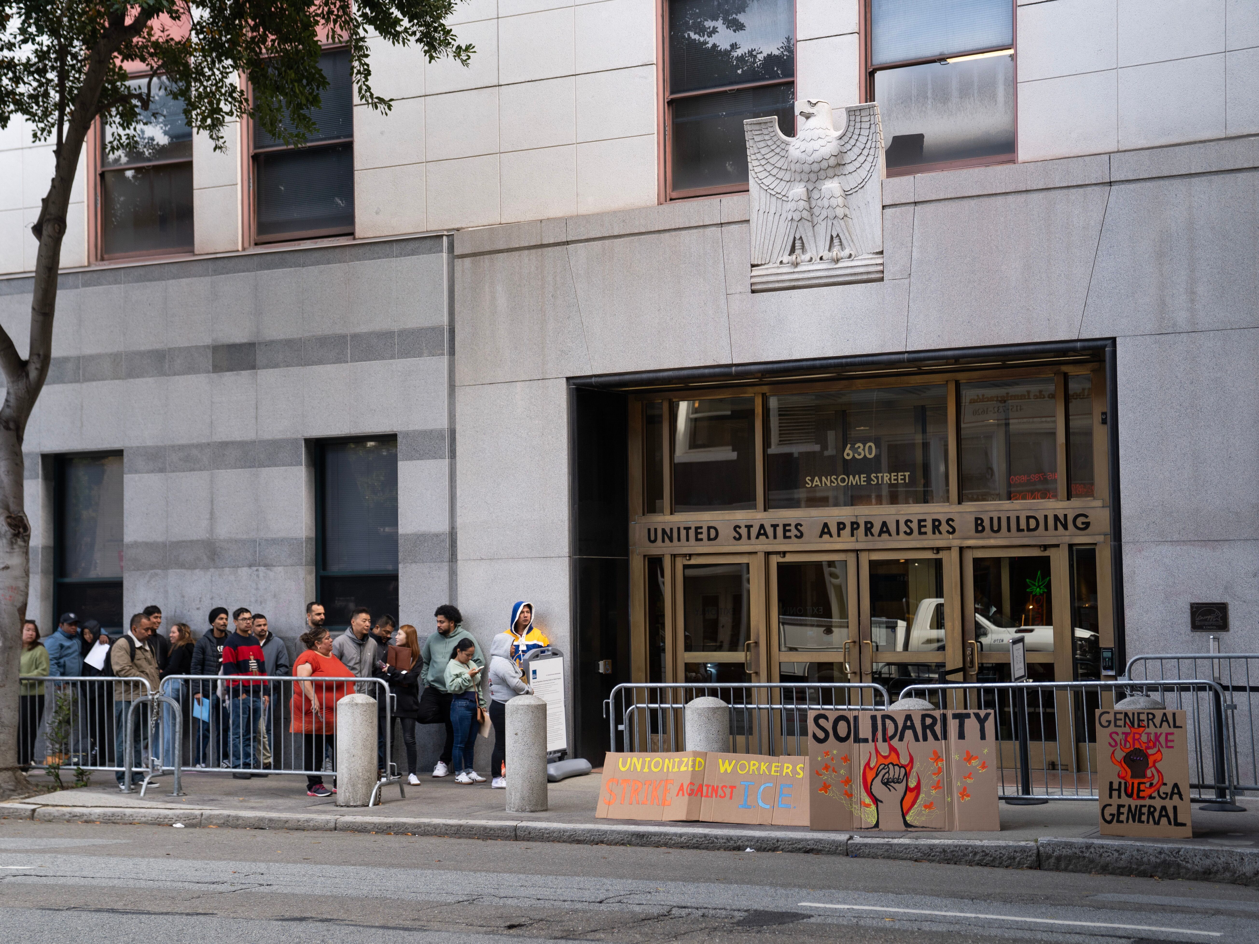 caption: People wait outside immigration court in October 2025 in San Francisco.