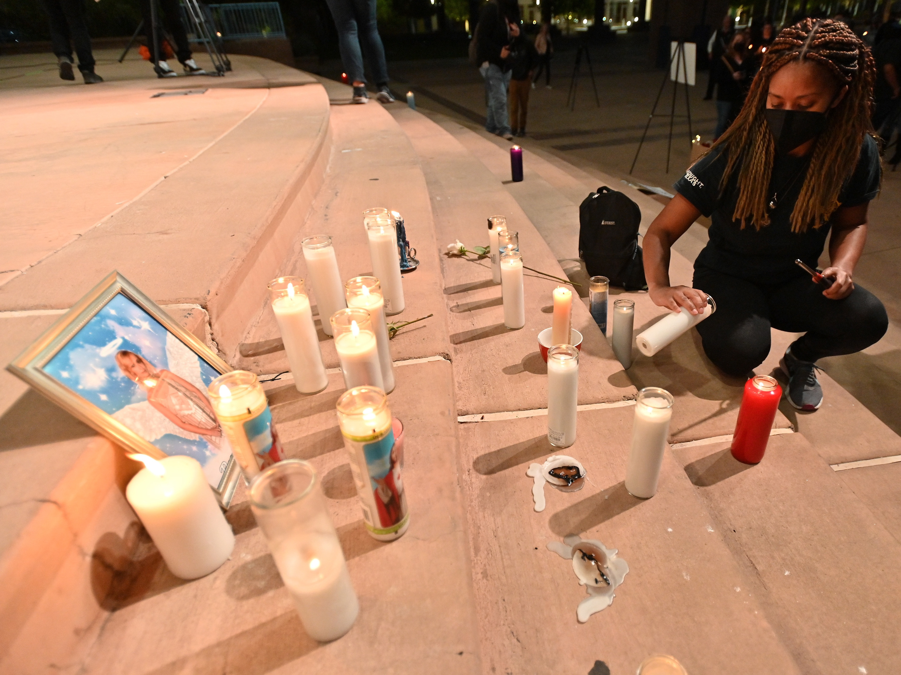 caption: Sarah Wilkinson lights a candle during a vigil held to honor cinematographer Halyna Hutchins in Albuquerque on October 23.