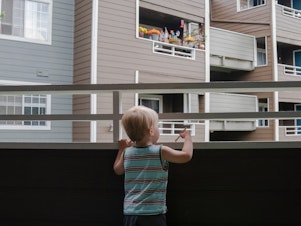 caption: Grigory Vodolazov's 3-year-old son peers into his family's apartment complex from their unit in Bellevue, Wash. The Vodolazov family is part of Creating Moves to Opportunity, a housing voucher experiment that uses incentives and counseling to encourage low-income families to move to what are called "high opportunity" areas.