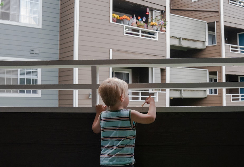 caption: Grigory Vodolazov's 3-year-old son peers into his family's apartment complex from their unit in Bellevue, Wash. The Vodolazov family is part of Creating Moves to Opportunity, a housing voucher experiment that uses incentives and counseling to encourage low-income families to move to what are called "high opportunity" areas.