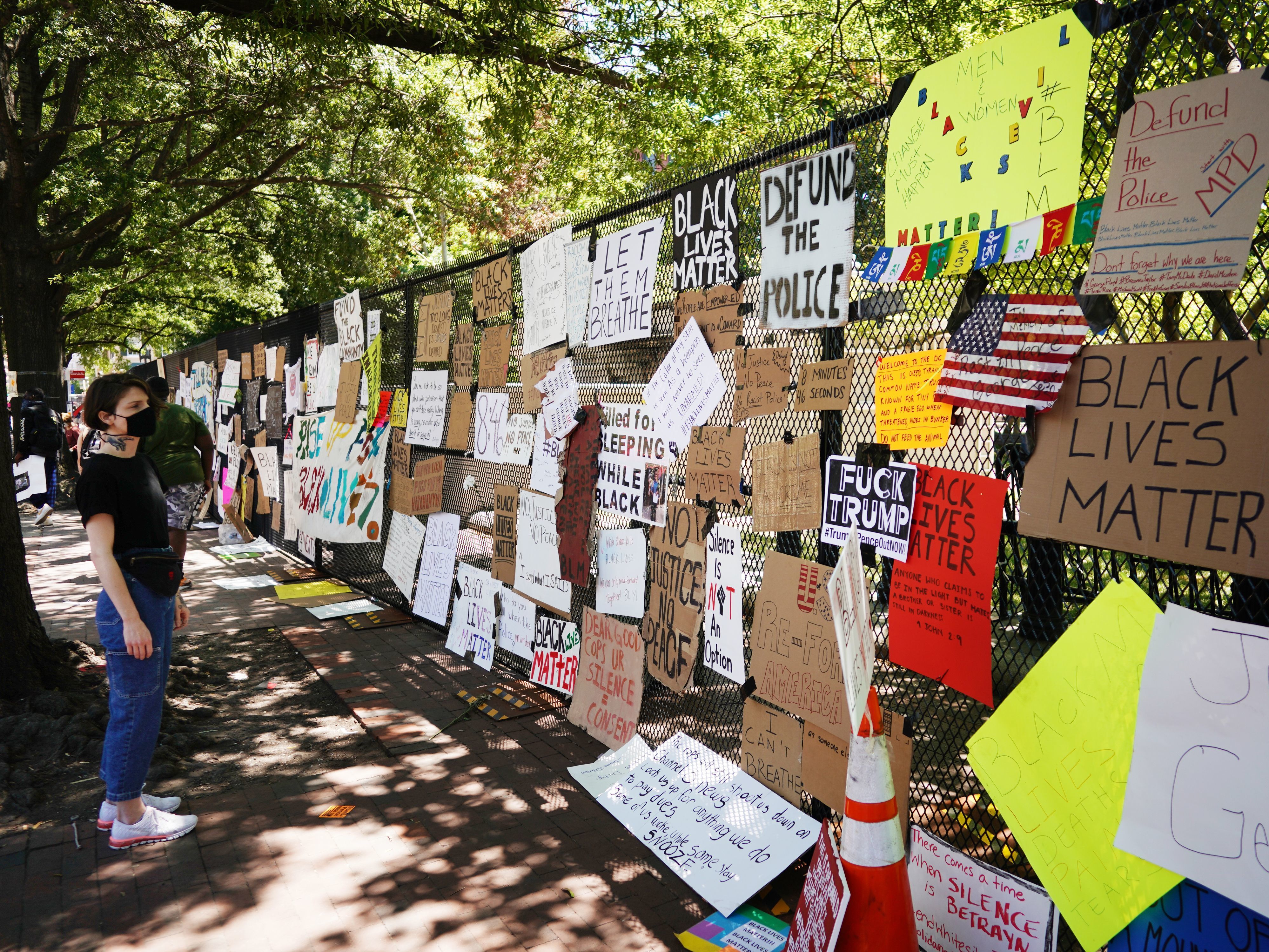 caption: A woman looks at messages attached to the security fence on the north side of Lafayette Square, near the White House, on Monday.