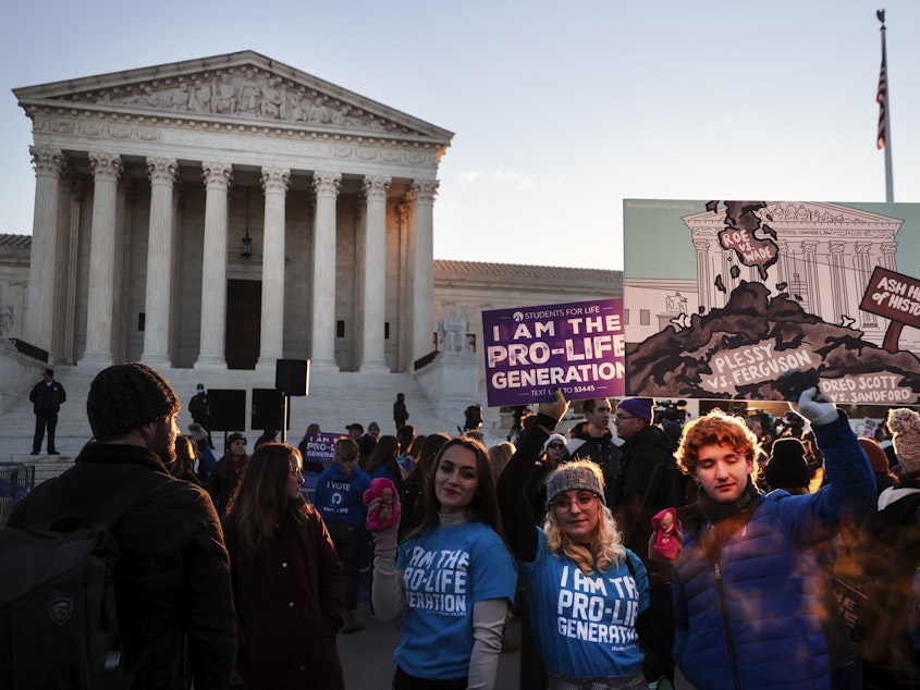 caption: Activists and demonstrators gather in front of the U.S. Supreme Court as the justices hear arguments in Dobbs v. Jackson Women's Health.