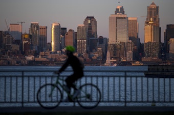 caption: A cyclist rides along Harbor Avenue Southwest as the sun sets on Tuesday, March 19, 2019, in Seattle. 