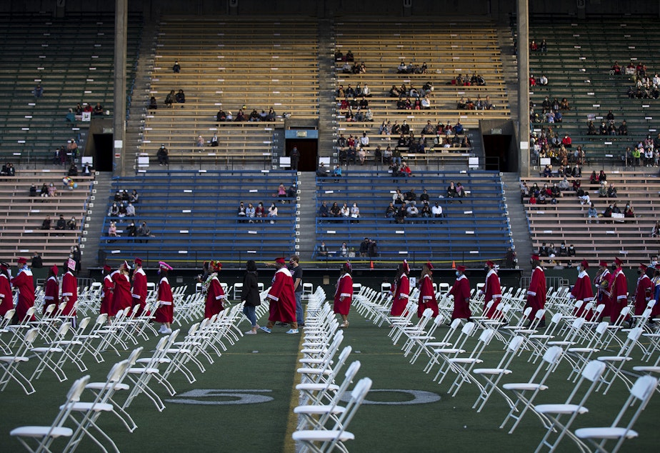 caption: Cleveland Stem High School seniors line up before taking their seats ahead of the in-person commencement ceremony on Tuesday, June 15, 2021, at Memorial Stadium in Seattle.
