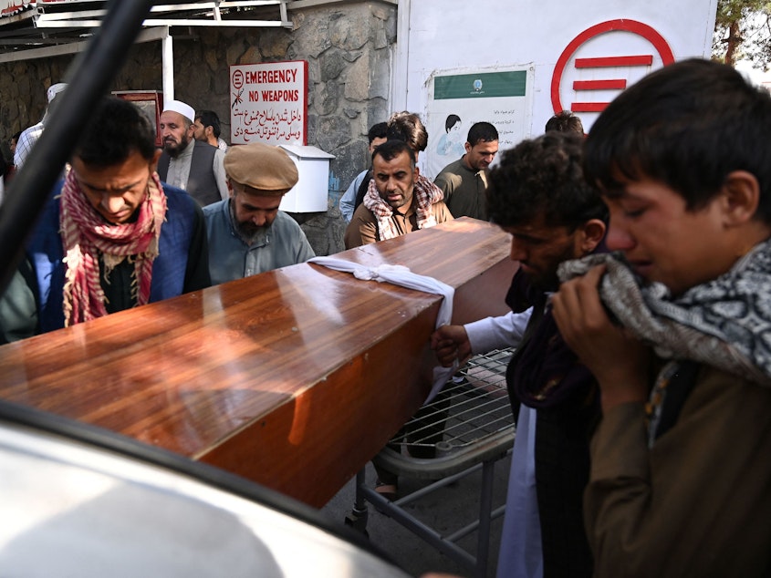 caption: Relatives on Friday load in a car the coffin of a victim of Thursday's explosions, which killed scores of people including 13 U.S. troops outside Kabul's airport, at a hospital run by the Italian NGO Emergency.