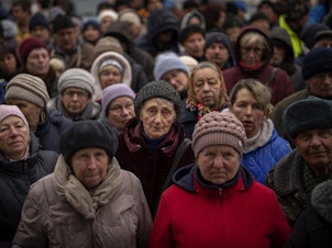 caption: <strong>April 18:</strong> Ukrainians wait as Red Cross relief workers distribute food in Bucha, on the outskirts of Kyiv, Ukraine.