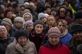 caption: <strong>April 18:</strong> Ukrainians wait as Red Cross relief workers distribute food in Bucha, on the outskirts of Kyiv, Ukraine.