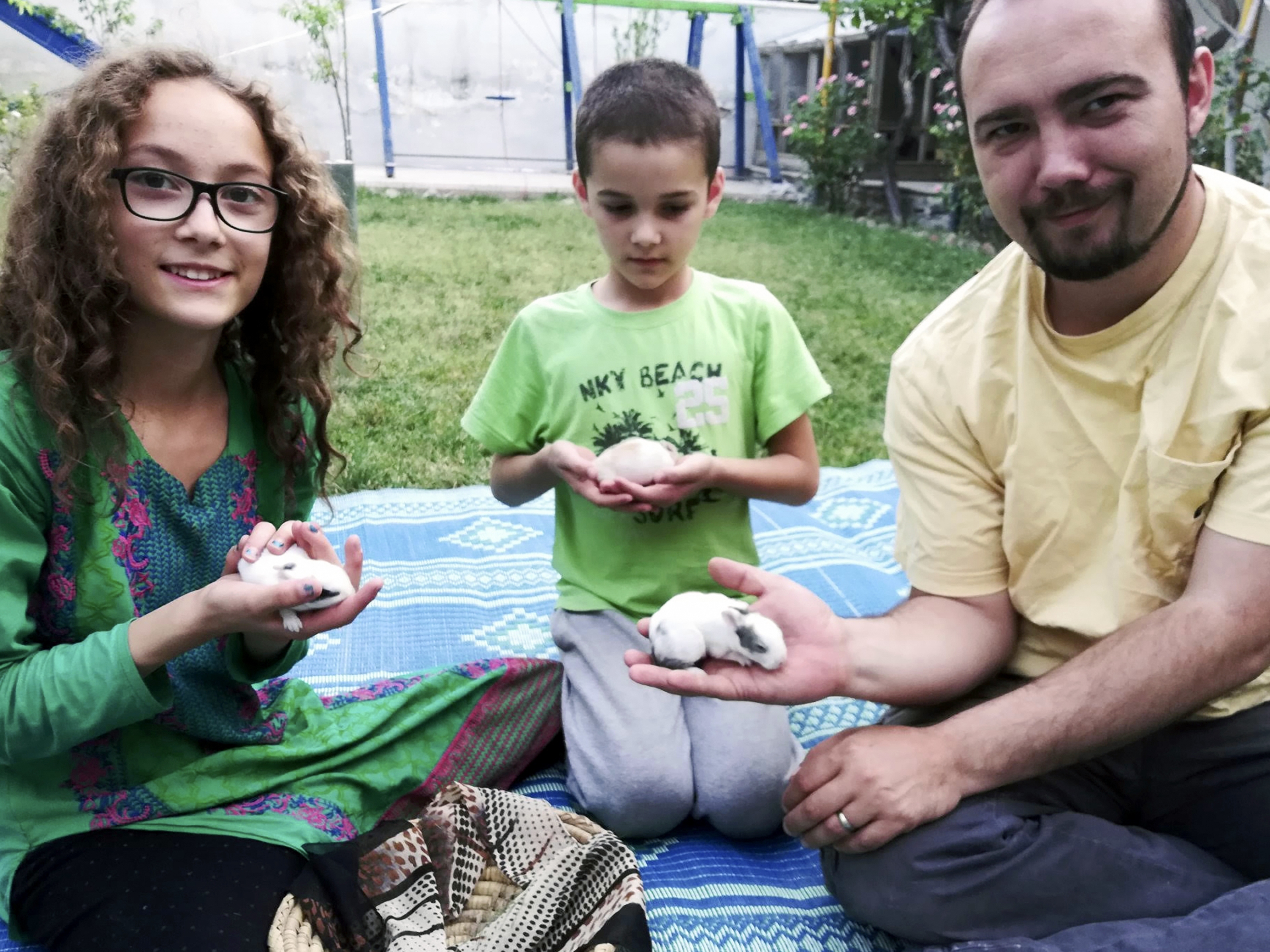 caption: This family photo shows Ryan Corbett holding rabbits with his daughter Miriam and son Caleb in Kabul, Afghanistan in 2020.