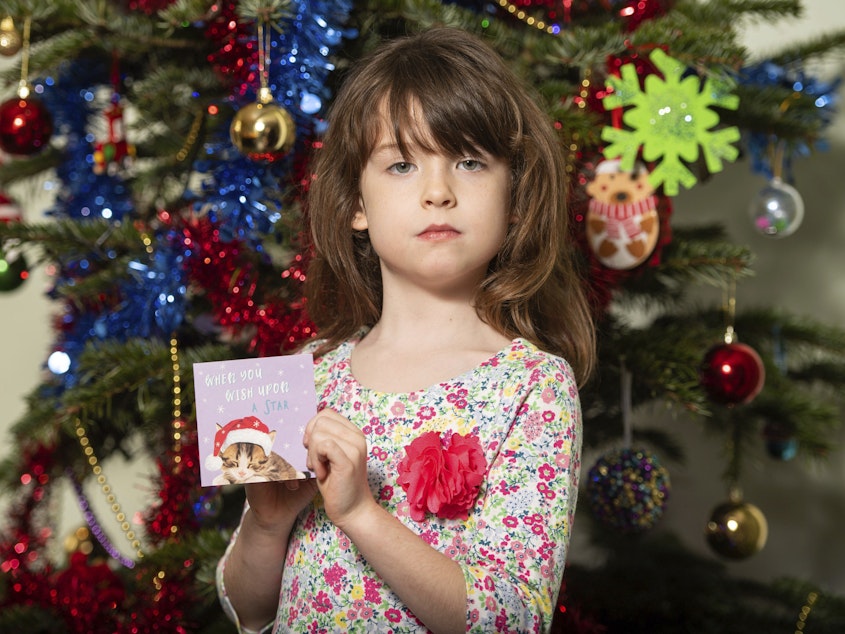 caption: Florence Widdicombe, 6, poses with a Christmas card from the same pack as a card she found containing a message apparently from a Chinese prisoner. The U.K.-based grocery chain Tesco has halted production at the factory in China that supplied the cards.