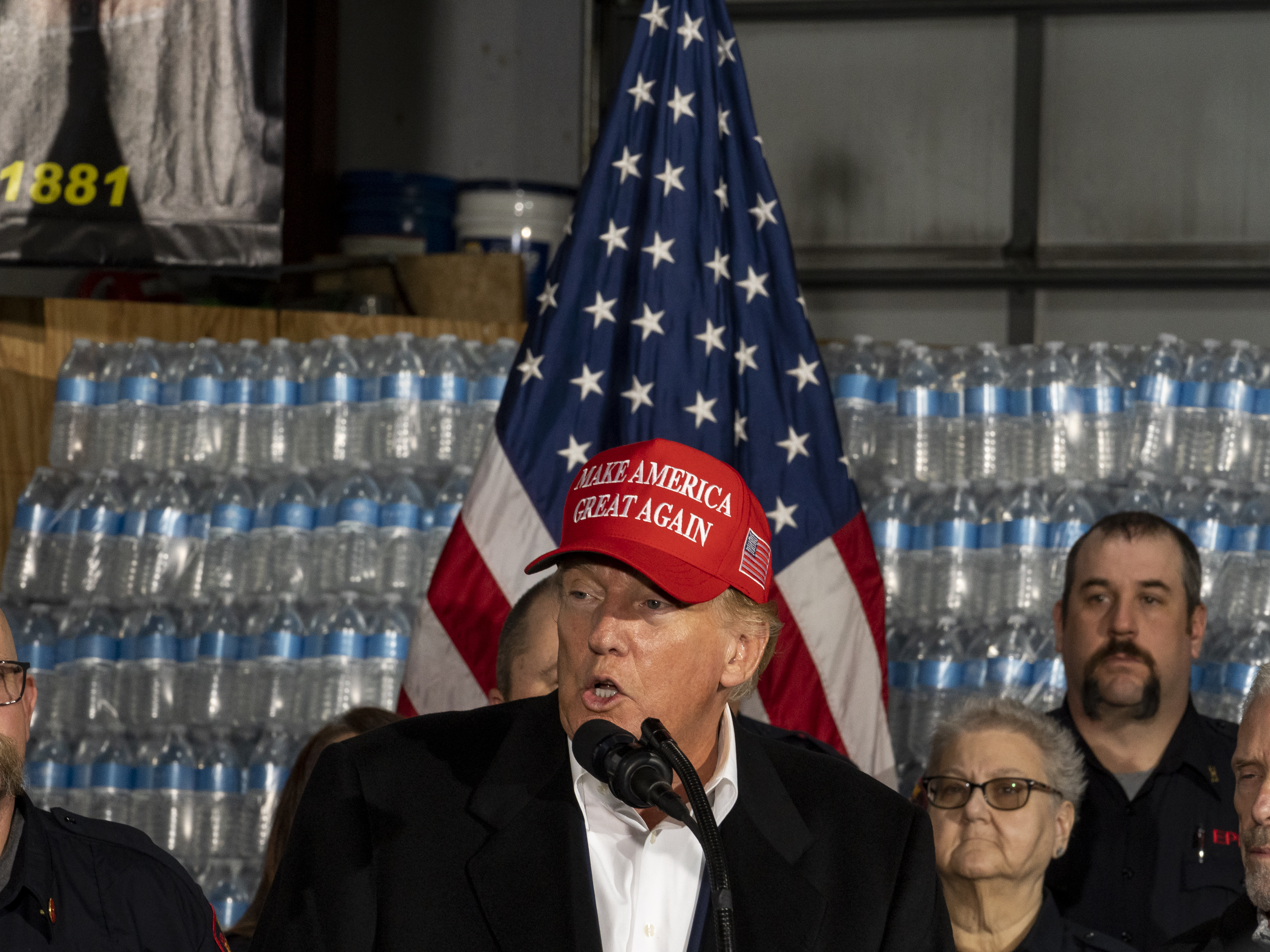 caption: During a visit to East Palestine, Ohio, former President Trump stands in front of a pallet of "Trump"-branded water before delivering remarks at the East Palestine Fire Department station Wednesday.