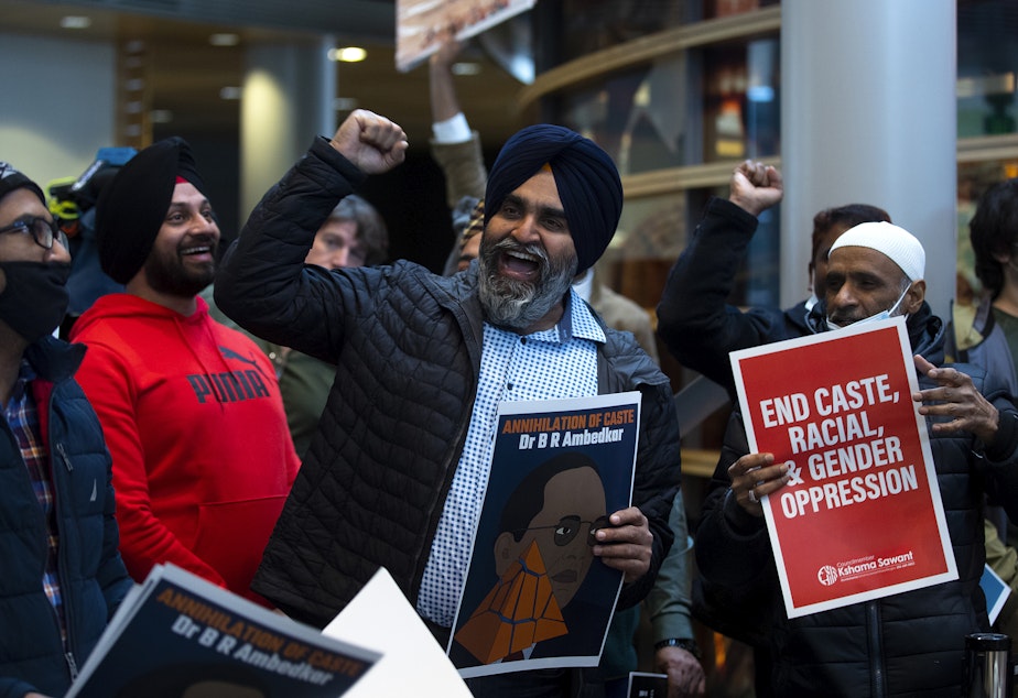 caption: Hira Singh Bhullar, center, raises his fist in the air while leading a chant during a rally ahead of a Seattle city council vote on a measure sponsored by councilmember Kshama Sawant that would ban discrimination based on caste, on Tuesday, February 21, 2023, at Seattle City Hall. Seattle would be the first city in the nation to do so. 