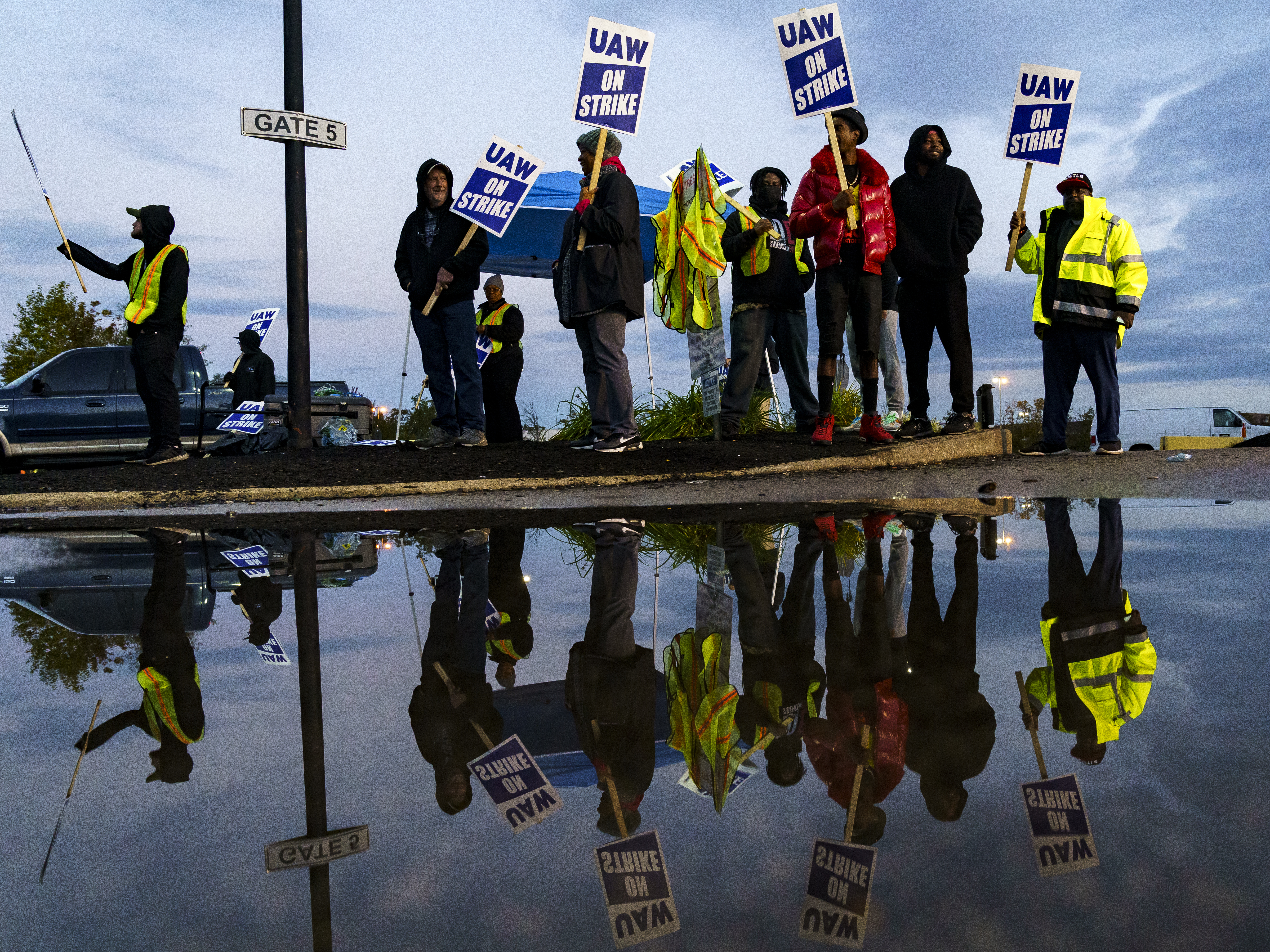 caption: Factory workers and UAW union members form a picket line outside the Ford Motor Co. Kentucky Truck Plant in the early morning hours on October 14, 2023 in Louisville, Kentucky.