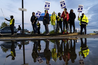 caption: Factory workers and UAW union members form a picket line outside the Ford Motor Co. Kentucky Truck Plant in the early morning hours on October 14, 2023 in Louisville, Kentucky.