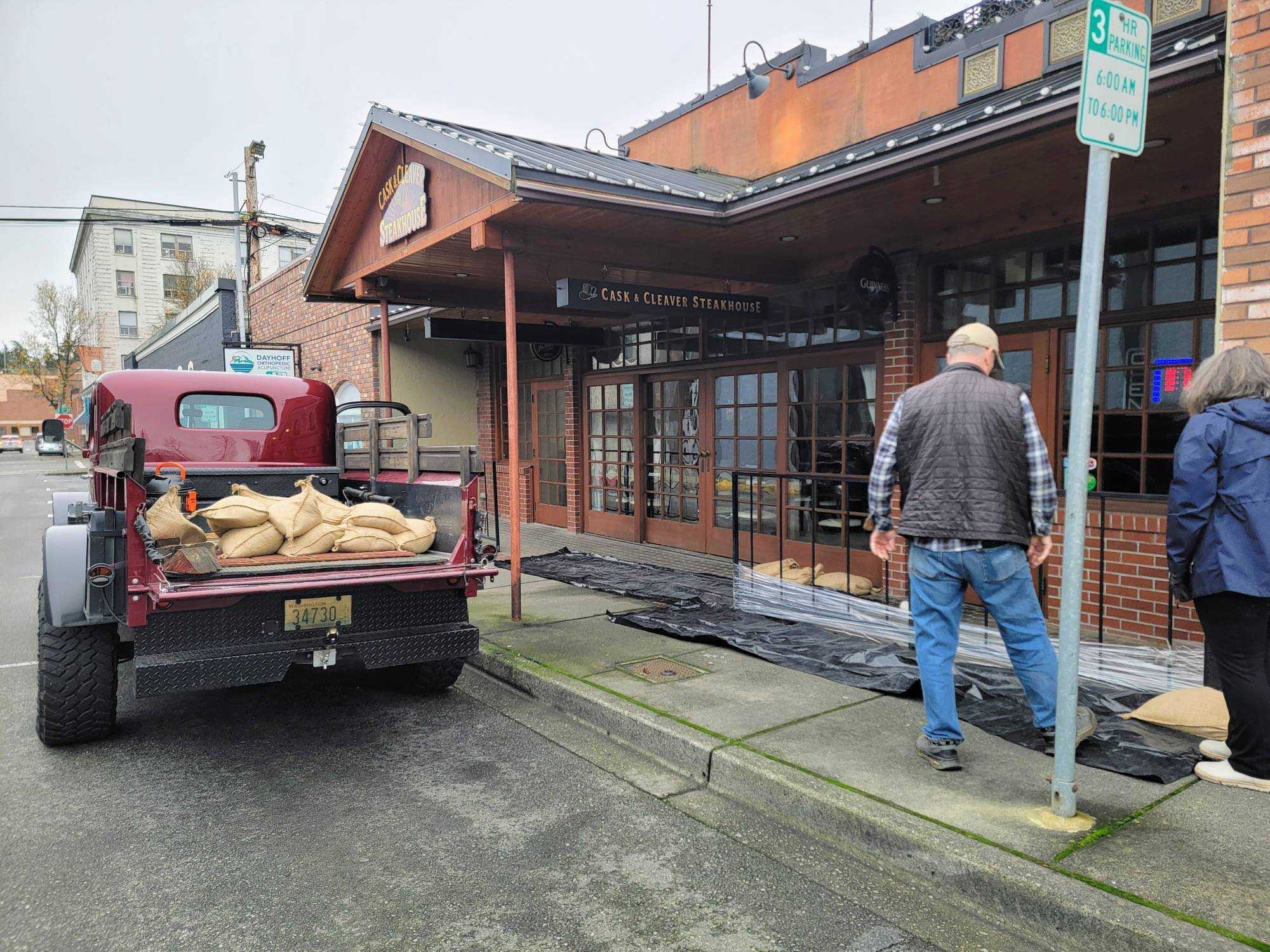 caption: Paul and Karin Springer put sandbags down in Mount Vernon. They say the city's flood wall leaked during flooding in 2021, so they want to be prepared.
