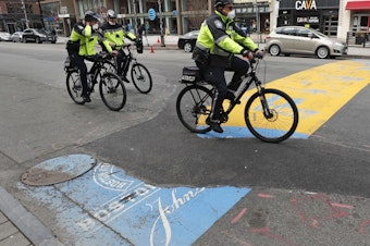 caption: Boston Police officers ride past the finish line of the Boston Marathon, which was canceled and replaced with a virtual event on Thursday.