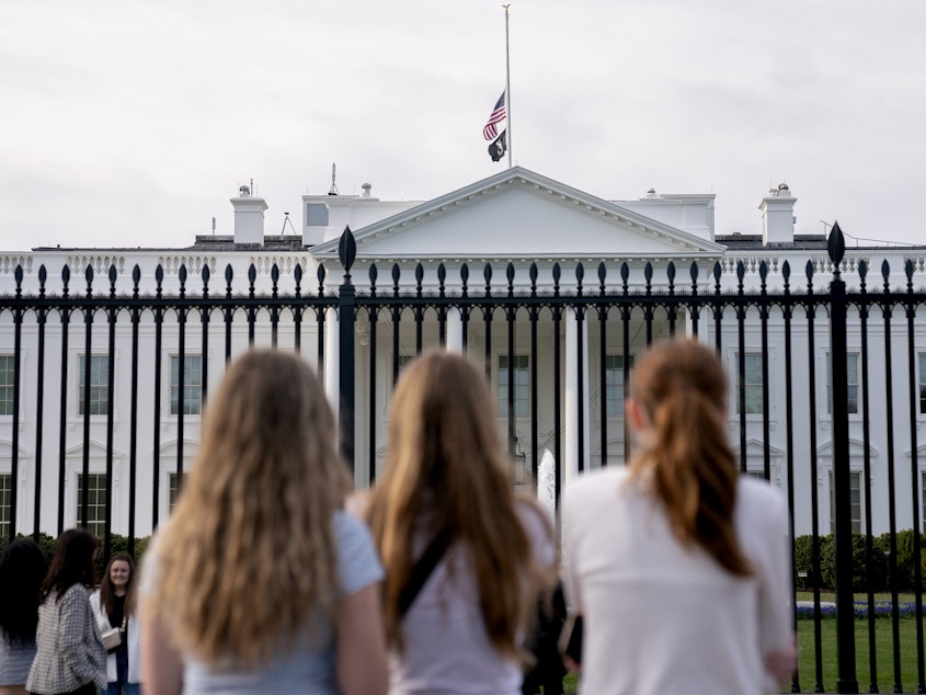 caption: Visitors look upon the White House as the US flag flies at half mast following a school shooting in Nashville, Tennessee last March.