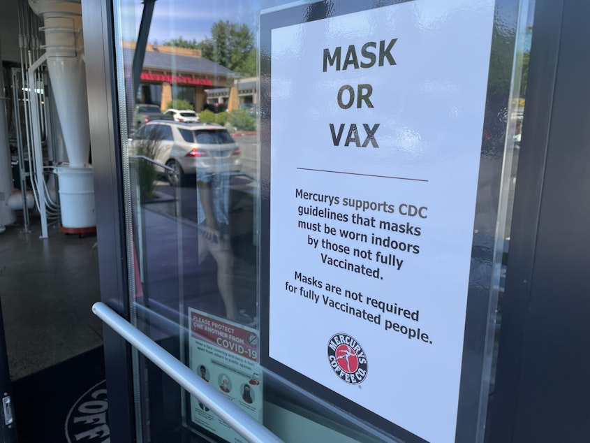 caption: A sign on the door of Mercury Coffee in Bellevue gives customers the option of nixing their masks if they are fully vaccinated. 