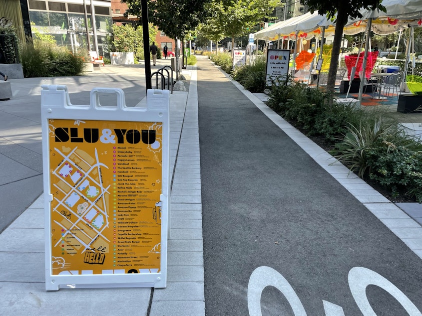 caption: SLU & You, part of Amazon's marketing campaign to draw attention to businesses on its campus. Visible at right, outdoor shelters created by Amazon in an attempt to liven up 6th Avenue