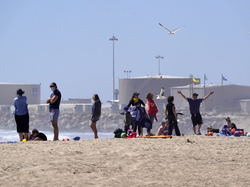 caption: Beachgoers return to Port Hueneme Beach, Calif., on Thursday. Ventura County beaches and parks have been scheduled to reopen this week with some restrictions.