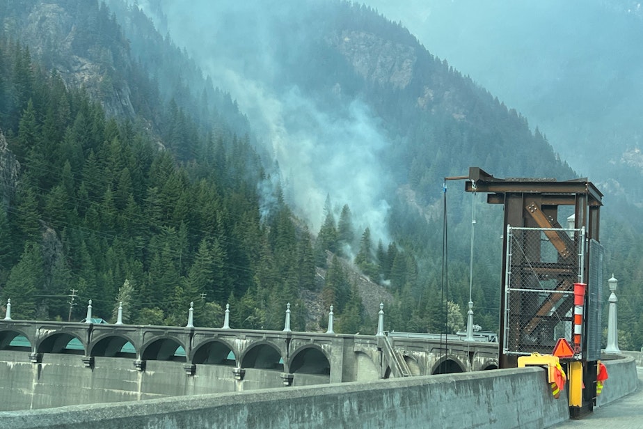 caption: The Sourdough Fire burns a slope in Washington's North Cascades, directly above Seattle City Light's Diablo Dam, on Aug. 6, 2023.