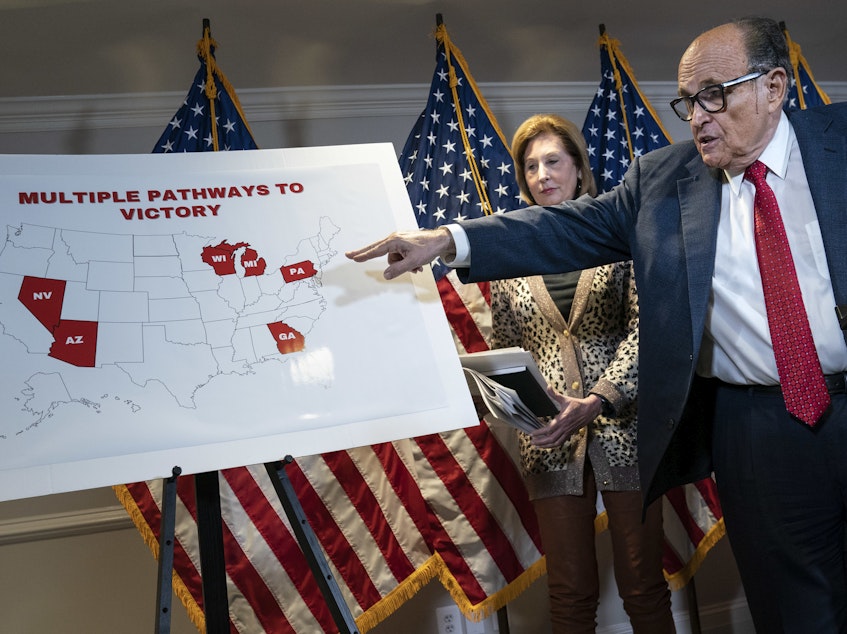 caption: President Trump's lawyer Rudy Giuliani points to a map as he speaks to the press about various lawsuits related to the 2020 election at the Republican National Committee headquarters on Thursday.