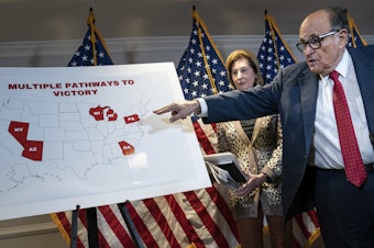 caption: President Trump's lawyer Rudy Giuliani points to a map as he speaks to the press about various lawsuits related to the 2020 election at the Republican National Committee headquarters on Thursday.