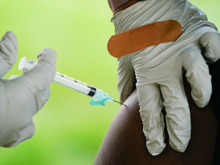 caption: A health worker administers a dose of a Pfizer COVID-19 vaccine during a vaccination clinic earlier this month at the Reading Area Community College in Reading, Pa.