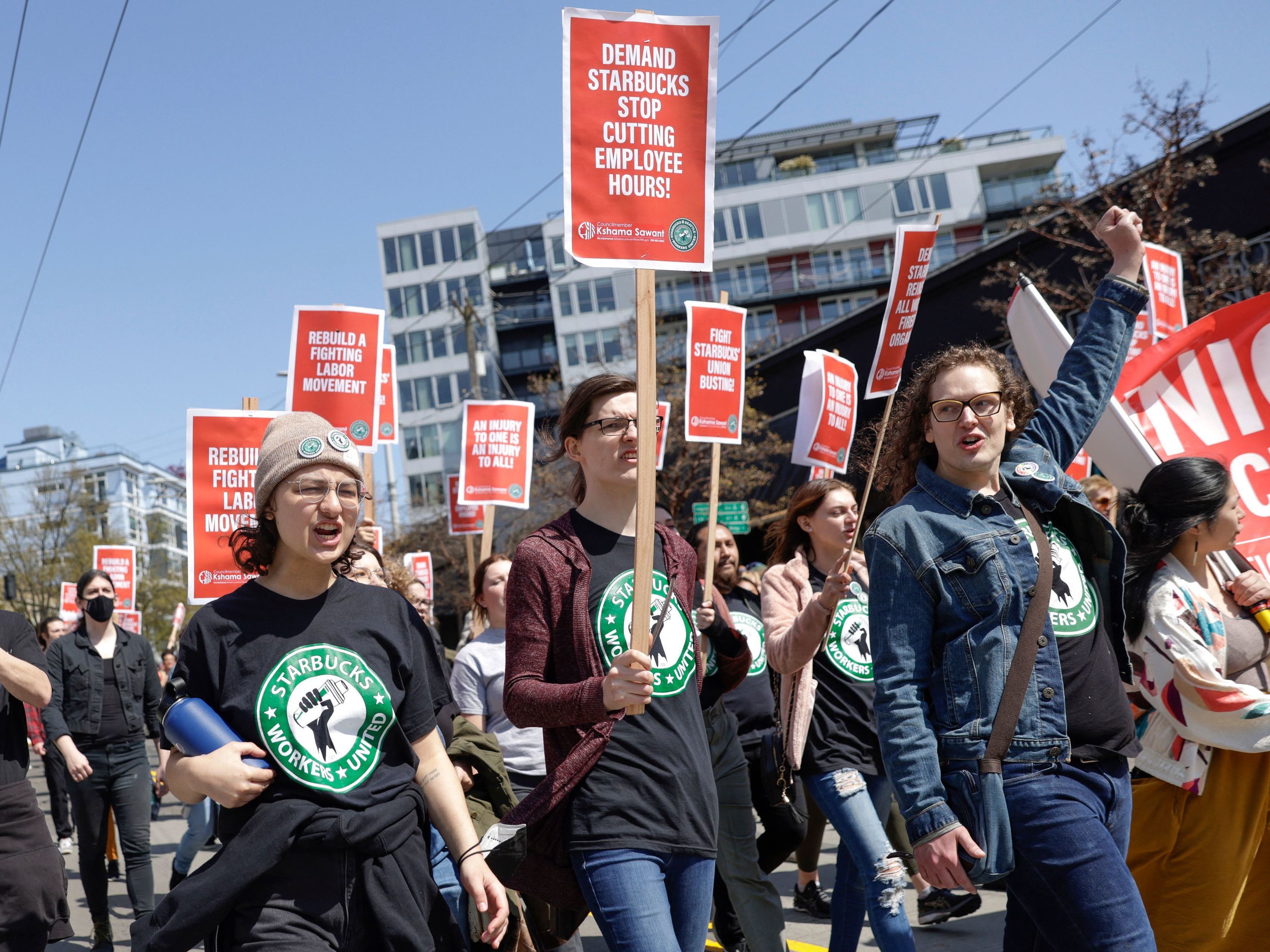caption: Protesters march in Seattle during the "Fight Starbucks' Union Busting" rally and march on April 23, 2022.