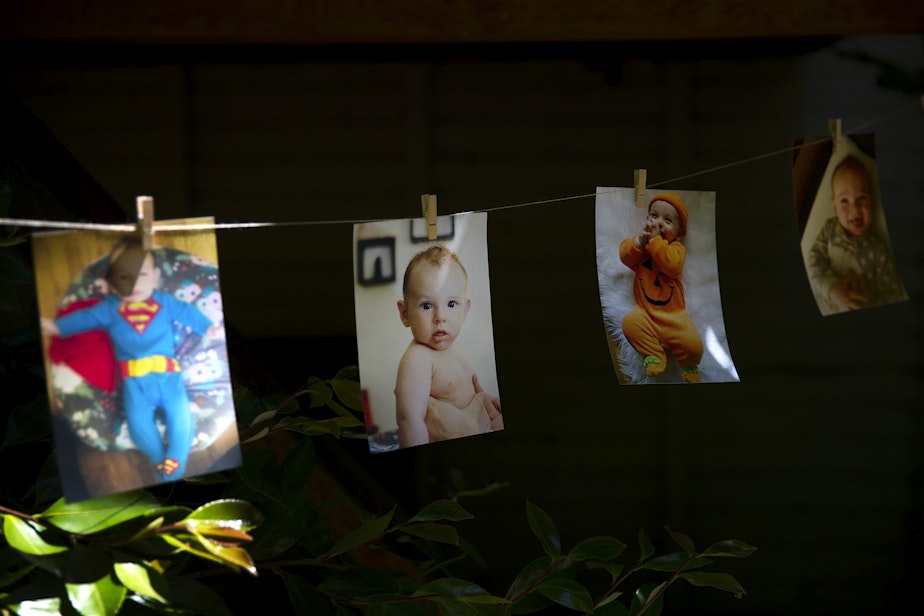 caption: Pictures of Arlo Philip hang from a string during his 1st birthday party on Saturday, May 29, 2021, at their home on Vashon Island. 