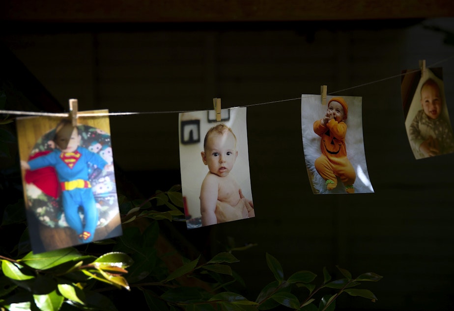 caption: Pictures of Arlo Philip hang from a string during his 1st birthday party on Saturday, May 29, 2021, at their home on Vashon Island.