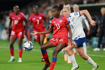 caption: Betina Petit-Frere of Haiti controls the ball against Alessia Russo of England during the teams' opening game at the Women's World Cup in Brisbane, Australia on July 22, 2023. Haiti is one of eight newcomers at the tournament this year.
