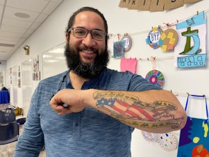 caption: Rafael Rivera's tattoo of an American Flag in the shape of Long Island, with a banner from John 15:13.