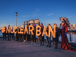 caption: People hold letters reading #NUCLEARBAN in New York City, in support of the Treaty on the Prohibition of Nuclear Weapons, which took effect on Friday.