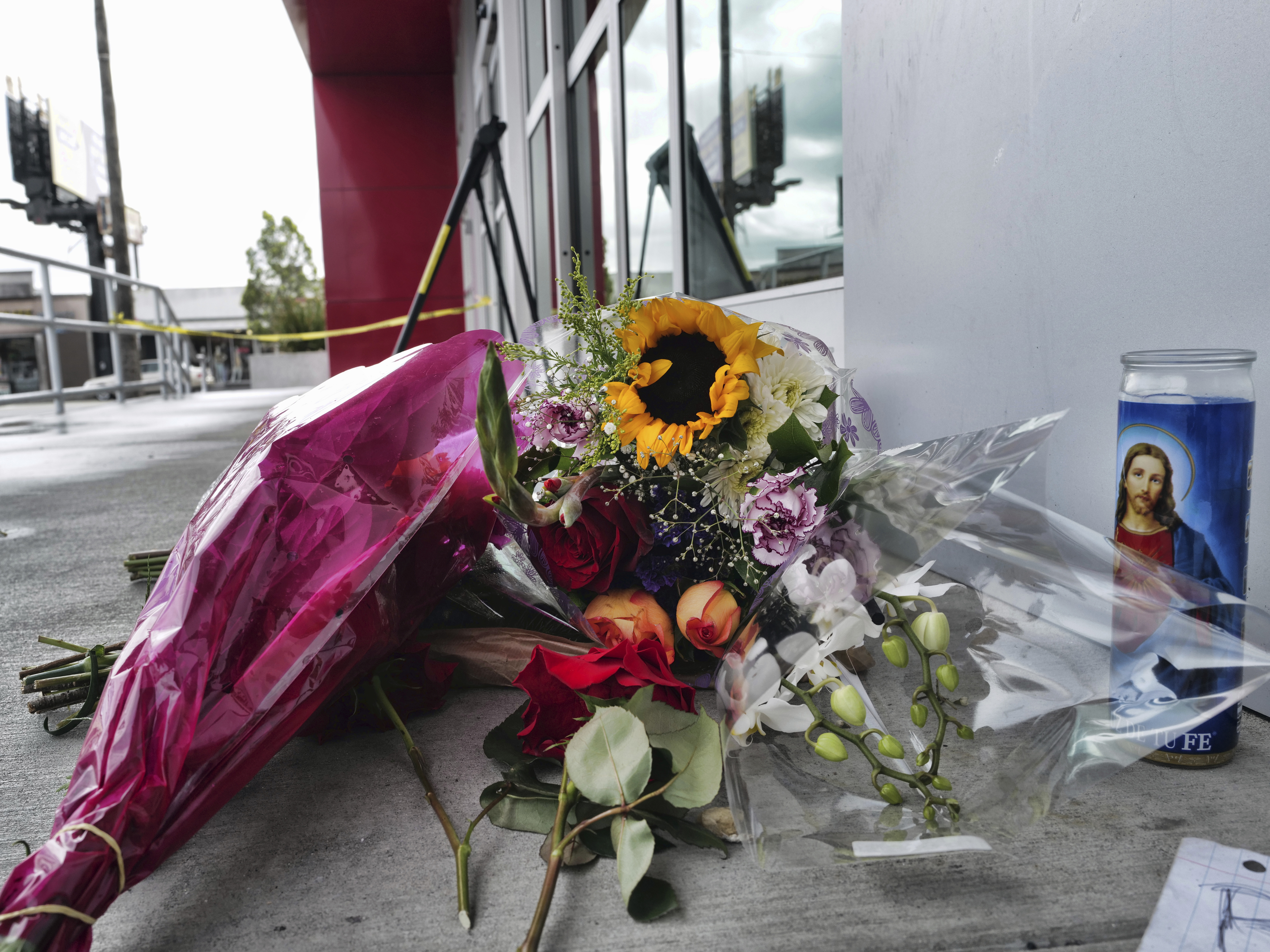 caption: A candle and flowers are left for a teen who was fatally shot at a department store in the North Hollywood section of Los Angeles.