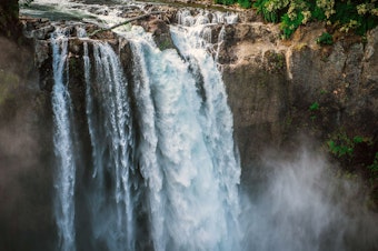 caption: Snoqualmie Falls can be seen with mist rising after hitting the plunge pool below. The falls are 268 feet, and are a popular scenic tourist attraction.