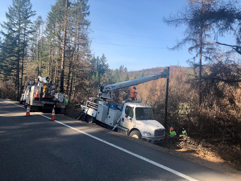 caption: Utility crews replace power poles burned in the Beachie Creek Fire east of Salem in September 2020.