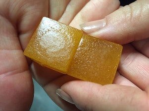 caption: An employee displays a limeade-flavored cannabis-infused gummy candy at the Chalice Farms industrial kitchen in Portland, Ore., in June 2016.