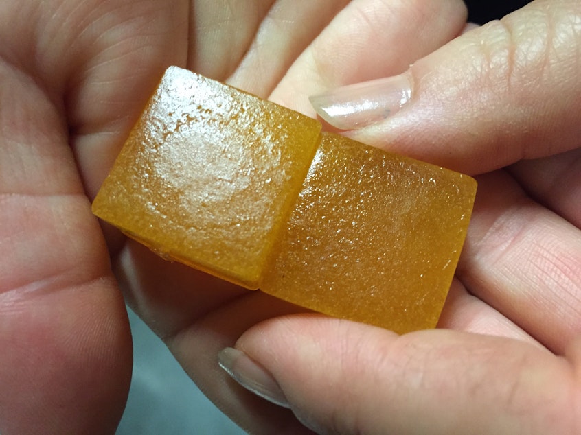 caption: An employee displays a limeade-flavored cannabis-infused gummy candy at the Chalice Farms industrial kitchen in Portland, Ore., in June 2016.