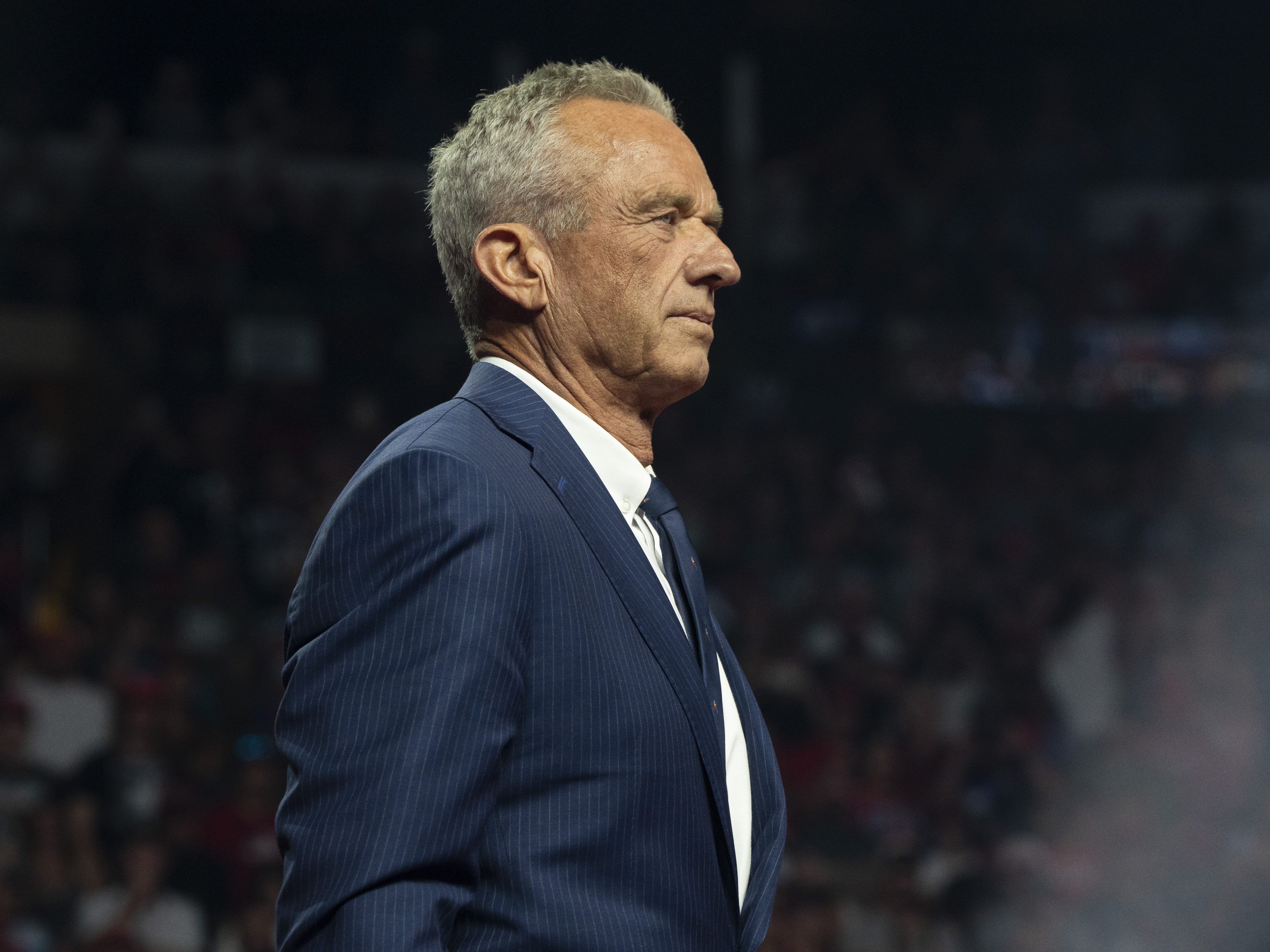 caption: Robert F. Kennedy Jr. listens during a campaign rally for Republican presidential nominee Donald Trump Friday in Glendale, Ariz. Kennedy suspended his independent presidential campaign and is backing Trump.