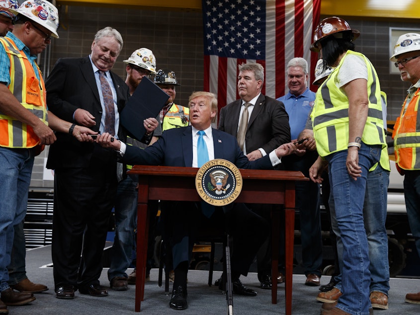 caption: President Trump hands out pens after signing an executive order aimed at making it easier for companies to pursue oil and gas pipeline projects. The president addressed an audience at the International Union of Operating Engineers International Training and Education Center in Texas.